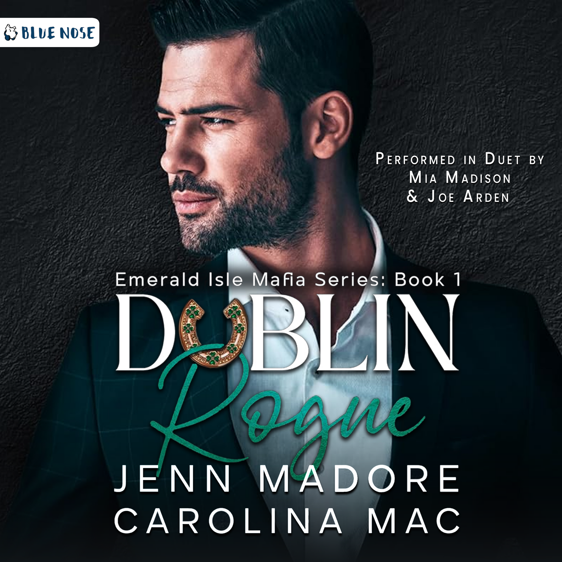 Dublin Rogue by Jenn Madore and Carolina Mac audiobook cover with a dark cement textured background and a bearded, dark-haired man in a suit looking screen left. His collar is open and he's not wearing a tie. Performed in Duet by Mia Madison and Joe Arden. Produced by Blue Nose AUDIO.